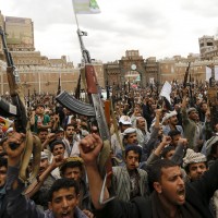 Shi'ite Muslim rebels hold up their weapons during a rally against air strikes in Sanaa