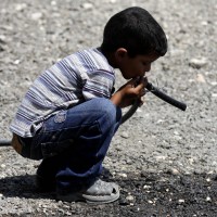 A Palestinian Bedouin child drinks water from a pipe near his tent on the road between Jericho and Ramallah
