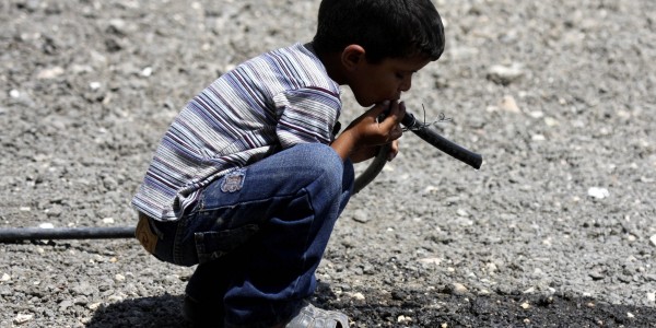 A Palestinian Bedouin child drinks water from a pipe near his tent on the road between Jericho and Ramallah