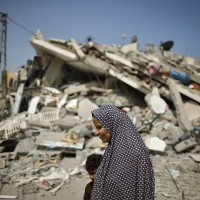 A Palestinian woman walks past the rubble of a residential building, which police said was destroyed in an Israeli air strike, in Gaza City