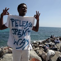 A migrant shouts a slogan as he wears a Tee Shirt with the message, "Open The Way" as he stands on the seawall at the Saint Ludovic border crossing on the Mediterranean Sea between Vintimille, Italy and Menton, France