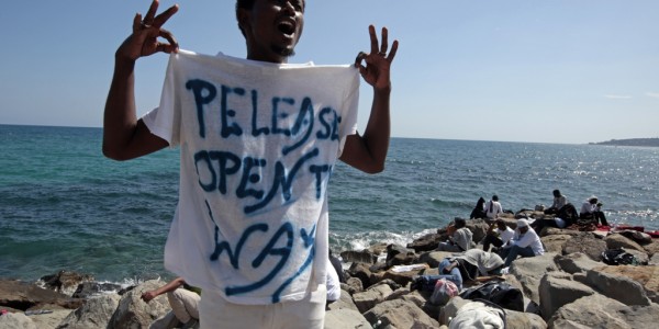 A migrant shouts a slogan as he wears a Tee Shirt with the message, "Open The Way" as he stands on the seawall at the Saint Ludovic border crossing on the Mediterranean Sea between Vintimille, Italy and Menton, France