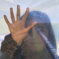 A migrant woman presses her hand against a plastic sheet while waiting for a daily food ration at the northern Greek border point of Idomeni, Greece, Saturday, March 19, 2016. German Chancellor Angela Merkel is urging migrants in the squalid tent city at Idomeni, on the Greek-Macedonian border, to trust Greek authorities and leave for better accommodation as thousands have stayed on site after the closure of Macedonia's border, clinging to hopes the Balkan route used for months by migrants heading for central Europe will reopen.(AP Photo/Vadim Ghirda)